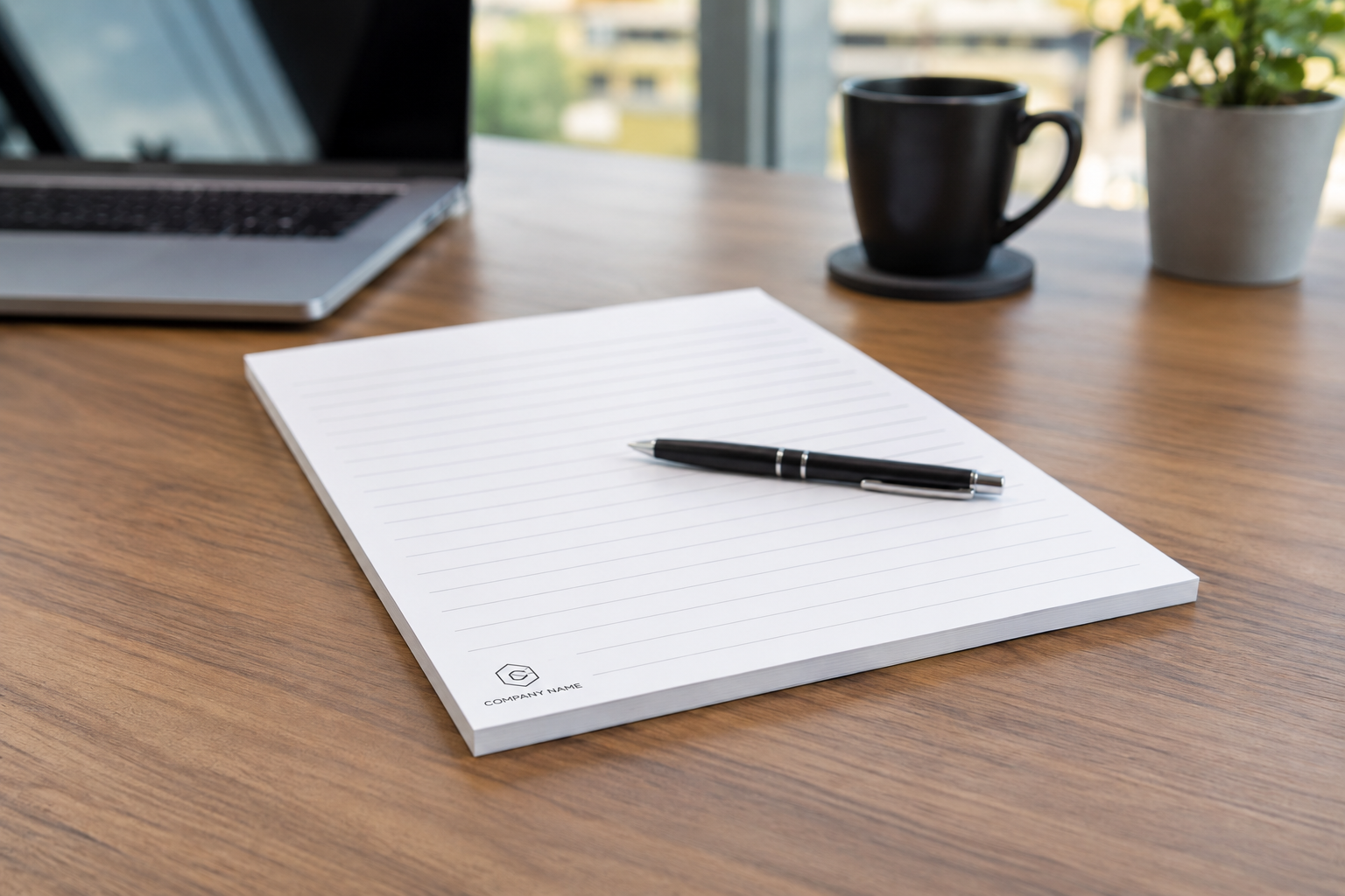 notes klejony 50 kartek notes klejony 50 kartkowy na biurku a na nim dlugopis. w tle filiżanka i laptop
